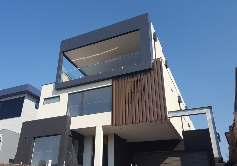 This is an example of a large contemporary three-storey house exterior in Melbourne with mixed siding, a flat roof and a metal roof.