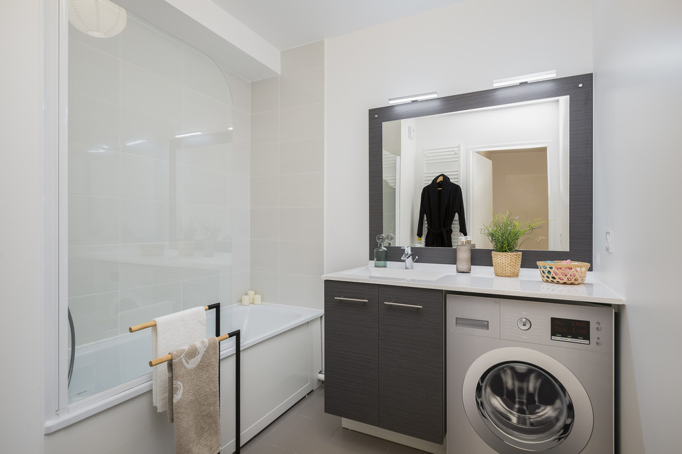 Idée de décoration pour une salle d'eau nordique avec un placard à porte plane, des portes de placard grises, une baignoire en alcôve, un combiné douche/baignoire, un carrelage beige, un mur gris, un lavabo intégré, un sol gris, aucune cabine et un plan de toilette blanc.