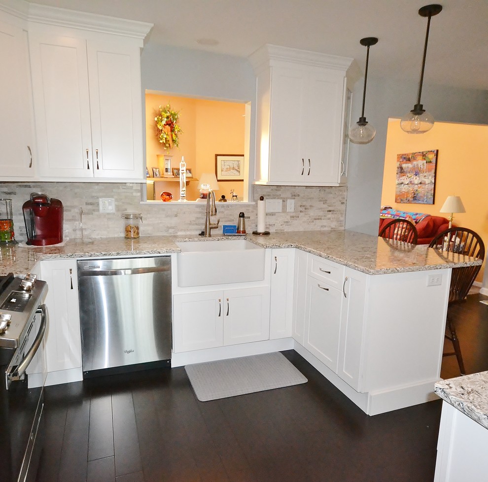 Mid-sized transitional l-shaped eat-in kitchen in Philadelphia with a farmhouse sink, flat-panel cabinets, white cabinets, quartz benchtops, beige splashback, ceramic splashback, stainless steel appliances, dark hardwood floors, a peninsula, brown floor and multi-coloured benchtop.