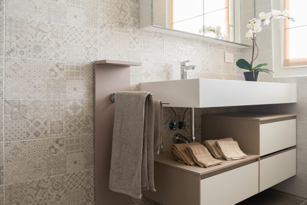 Medium sized contemporary ensuite bathroom in Milan with flat-panel cabinets, beige cabinets, a built-in bath, a two-piece toilet, beige tiles, porcelain tiles, white walls, porcelain flooring, a trough sink, solid surface worktops, brown floors, white worktops, a single sink and a floating vanity unit.