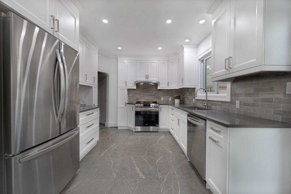 Enclosed kitchen - mid-sized transitional galley enclosed kitchen idea with an undermount sink, shaker cabinets, white cabinets, quartz countertops, gray backsplash, subway tile backsplash, stainless steel appliances, no island and gray countertops