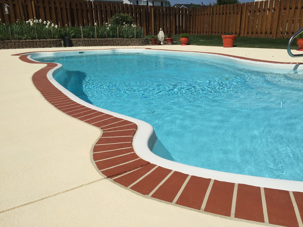 Photo of a mid-sized traditional backyard custom-shaped natural pool in St Louis with stamped concrete.