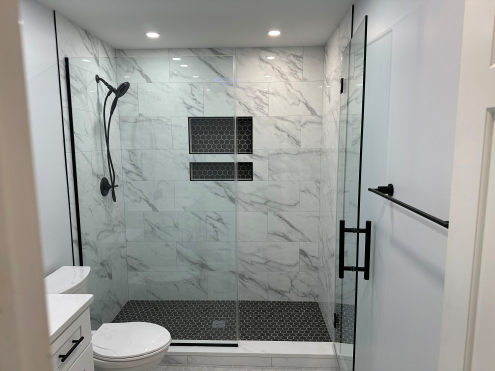 Inspiration for a medium sized modern ensuite bathroom in DC Metro with shaker cabinets, white cabinets, an alcove shower, a two-piece toilet, white tiles, porcelain tiles, grey walls, porcelain flooring, a submerged sink, quartz worktops, grey floors, a hinged door, white worktops, a wall niche, a single sink and a built in vanity unit.
