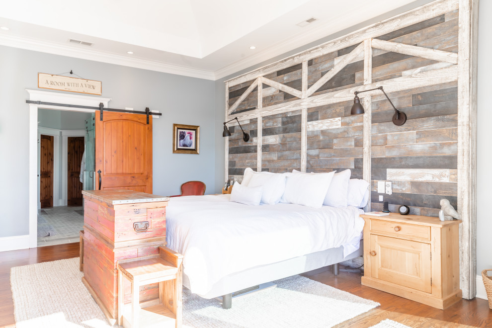 Diseño de dormitorio principal y abovedado campestre grande con paredes azules, suelo de madera en tonos medios, suelo marrón y madera