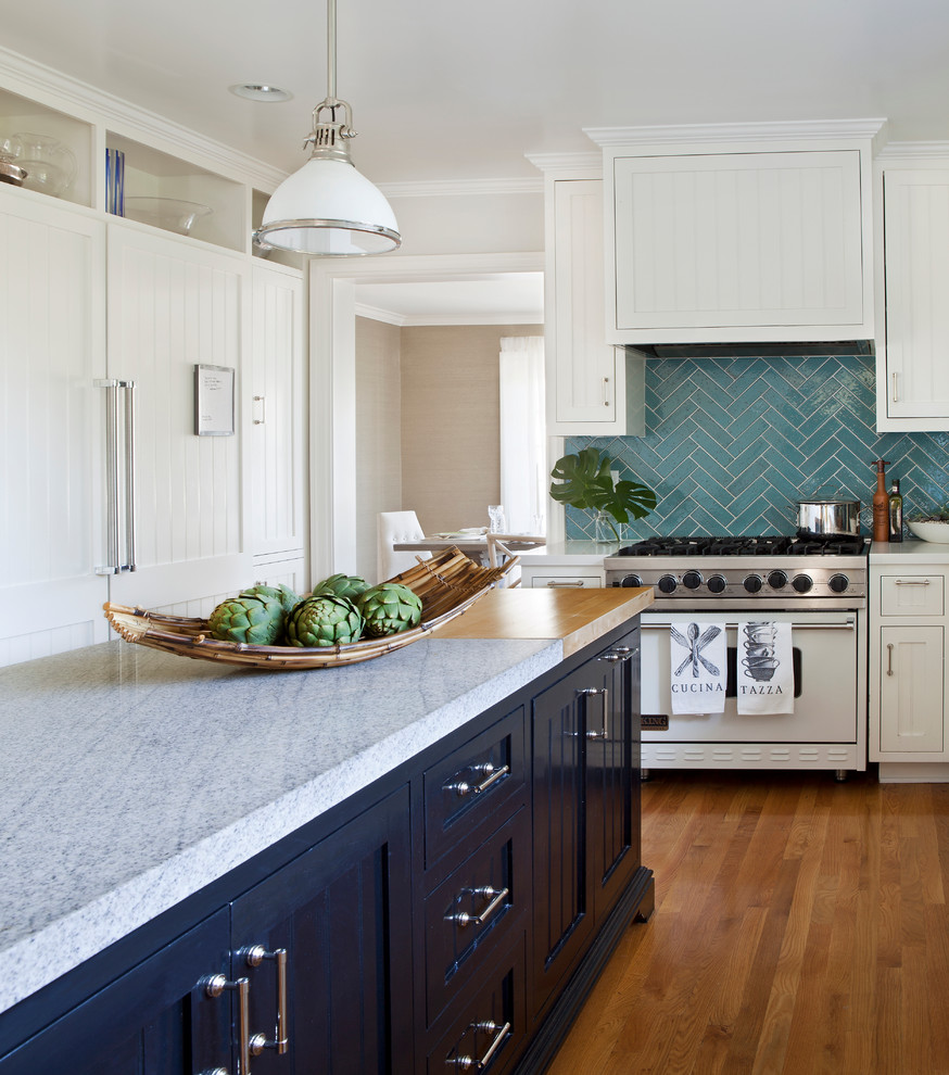 Photo of a mid-sized traditional l-shaped kitchen in Los Angeles with beaded inset cabinets, white cabinets, marble benchtops, blue splashback, cement tile splashback, white appliances, medium hardwood floors and with island.