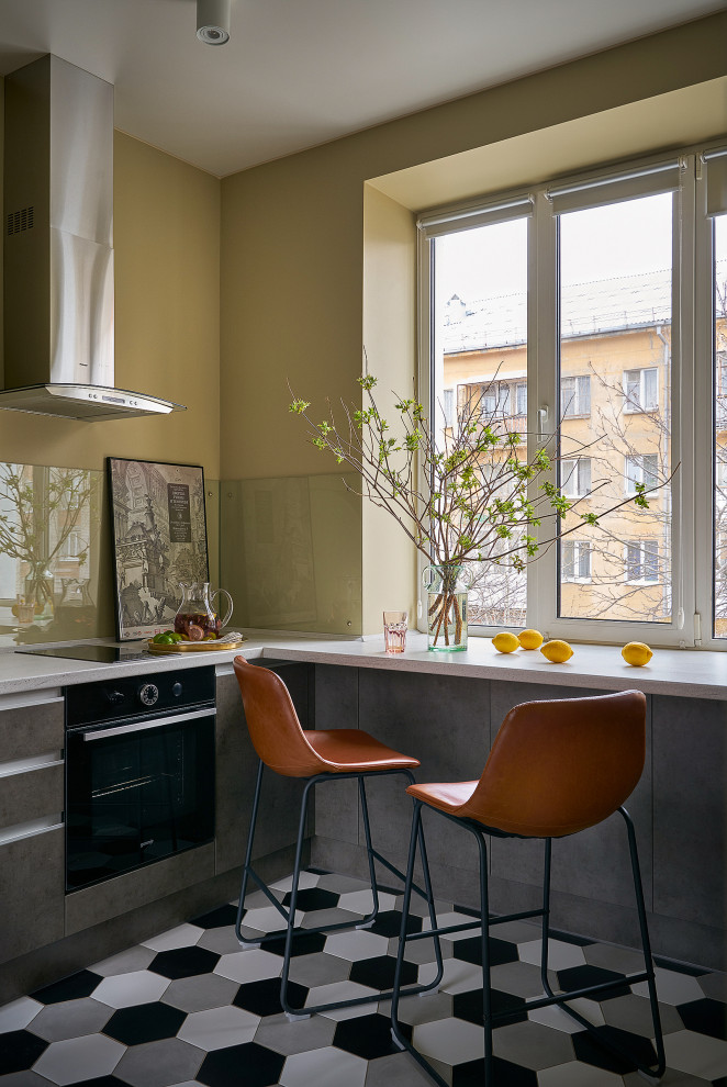 Photo of a small contemporary single-wall separate kitchen in Yekaterinburg with an undermount sink, flat-panel cabinets, grey cabinets, solid surface benchtops, beige splashback, glass sheet splashback, black appliances, ceramic floors, no island, multi-coloured floor, white benchtop and recessed.