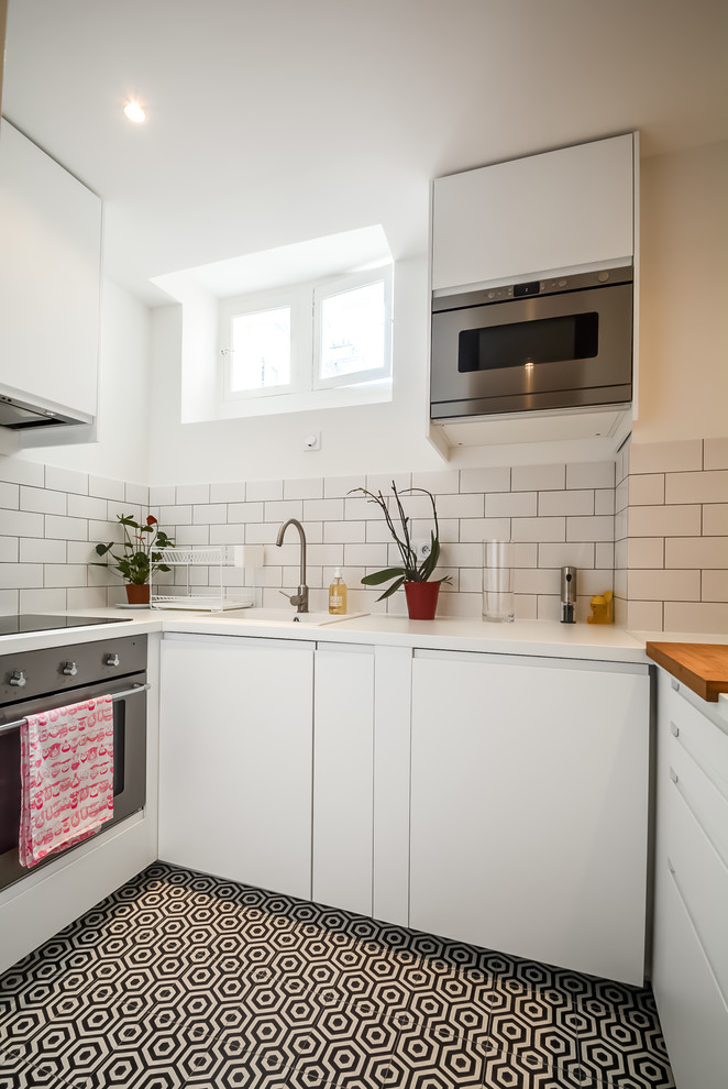 Small scandinavian u-shaped separate kitchen in Paris with a drop-in sink, flat-panel cabinets, white cabinets, white splashback, subway tile splashback, stainless steel appliances and no island.