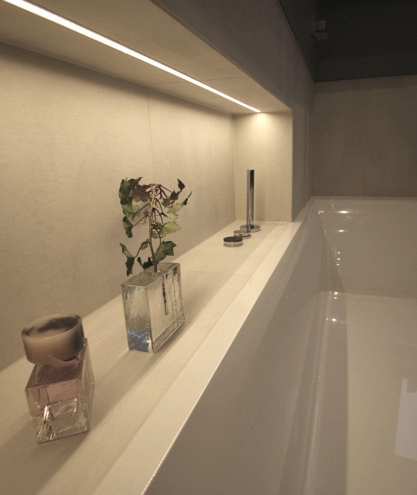 Design ideas for a large contemporary bathroom in Cologne with flat-panel cabinets, grey cabinets, a drop-in tub, a wall-mount toilet, white tile, ceramic tile, white walls, an integrated sink and grey floor.