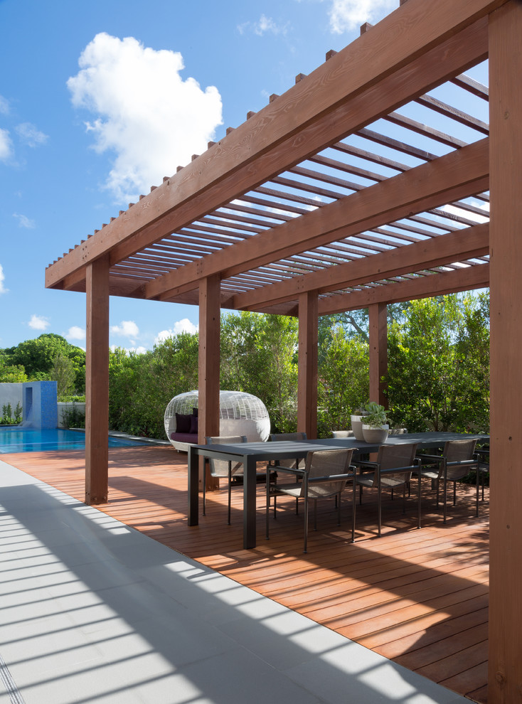 Photo of a mid-sized contemporary backyard deck in Miami with a water feature and a pergola.