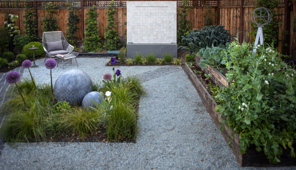 Cette image montre un jardin arrière design avec un point d'eau, une exposition partiellement ombragée, du gravier et une clôture en bois.