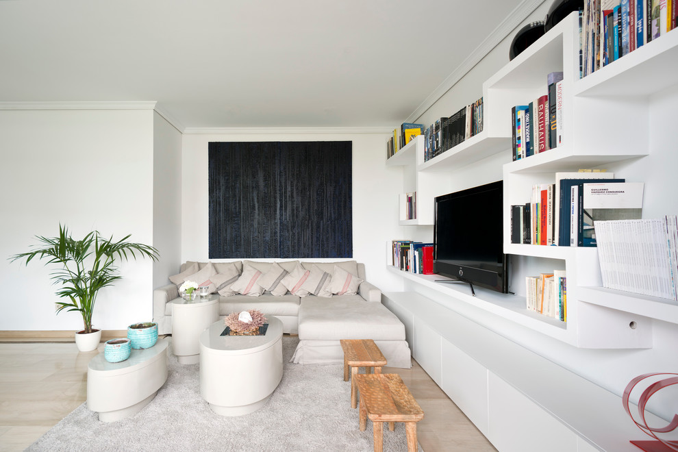Photo of a small contemporary open concept living room in Madrid with a library, white walls, marble floors and a freestanding tv.