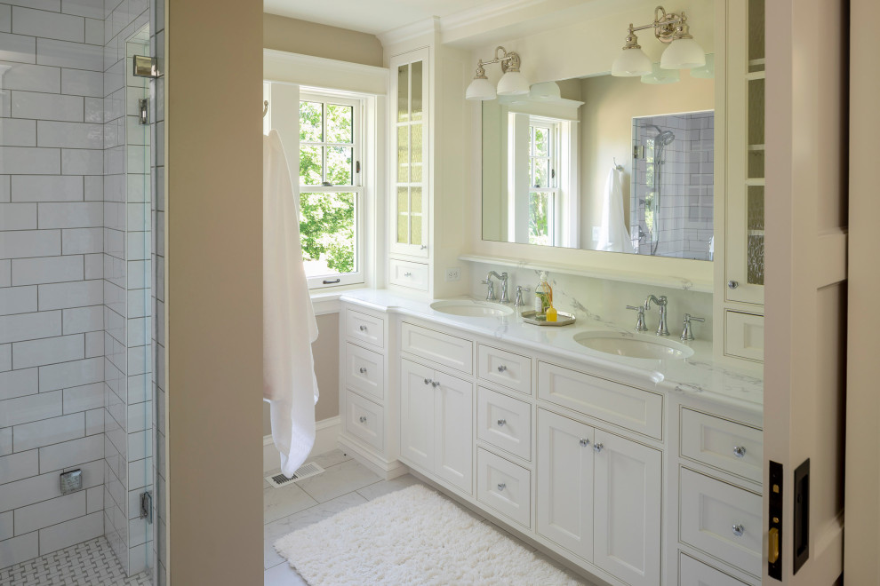 Photo of a mid-sized beach style master bathroom in Minneapolis with beaded inset cabinets, white cabinets, ceramic tile, beige walls, ceramic floors, an undermount sink, marble benchtops, multi-coloured benchtops, a double vanity and a built-in vanity.
