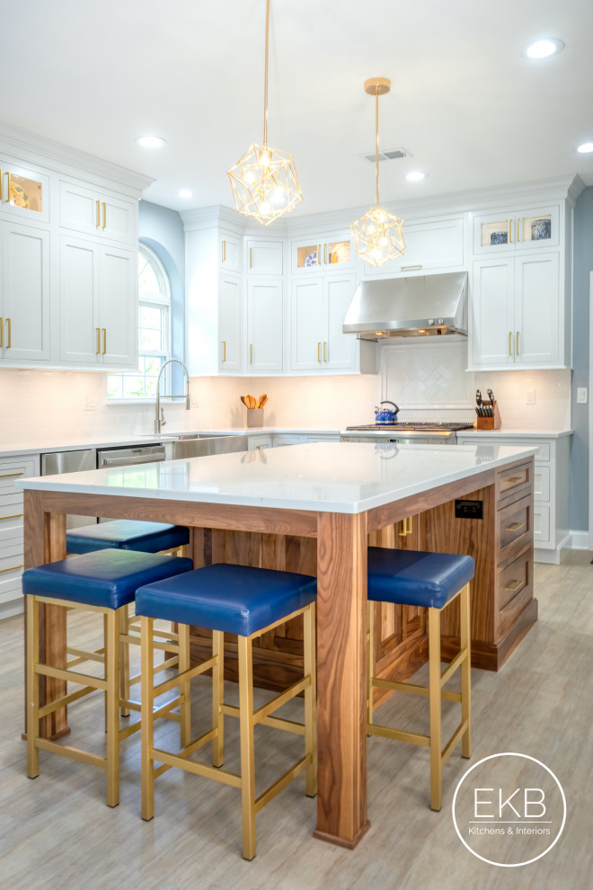 Large traditional l-shaped open plan kitchen in New York with a farmhouse sink, shaker cabinets, white cabinets, quartz benchtops, white splashback, ceramic splashback, stainless steel appliances, light hardwood floors, with island, grey floor and white benchtop.