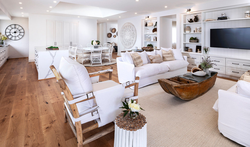 Large beach style open concept living room in Other with white walls, medium hardwood floors, a built-in media wall and brown floor.