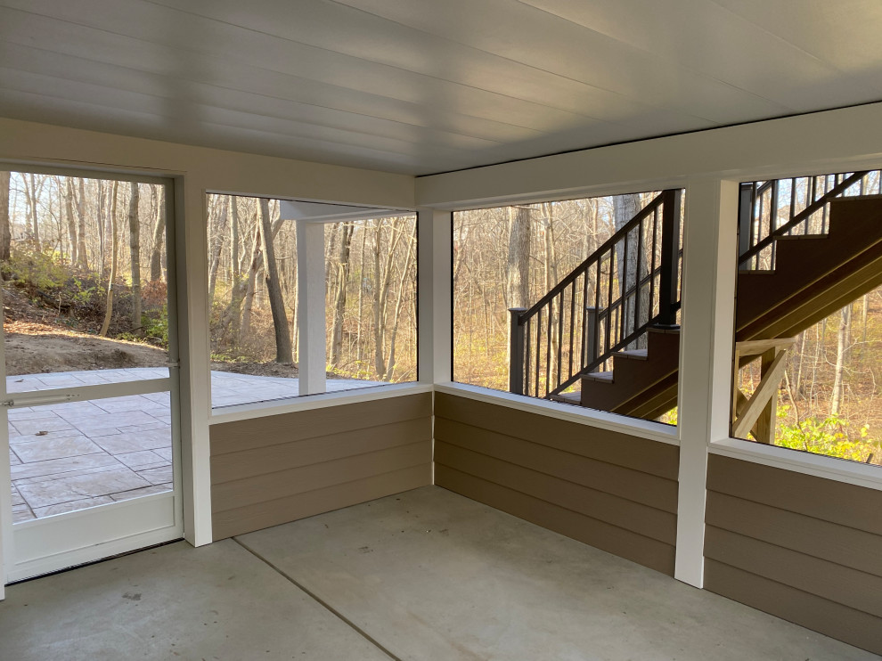 Large transitional backyard and first floor deck in Cincinnati with a roof extension and metal railing.