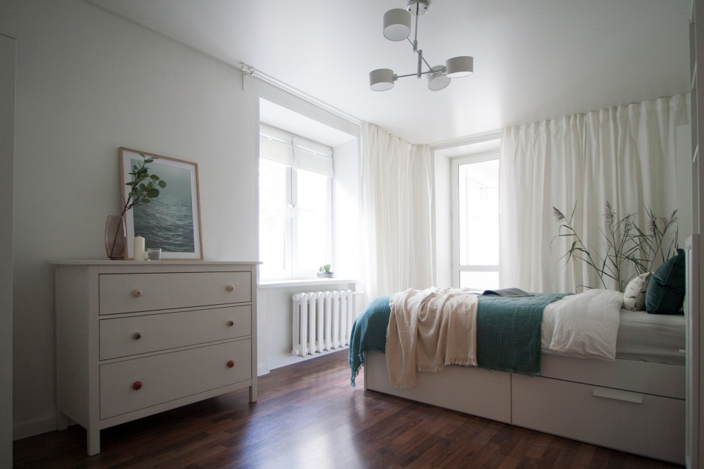 На фото: маленькая спальня в белых тонах с отделкой деревом в скандинавском стиле с белыми стенами, полом из ламината и коричневым полом для на участке и в саду