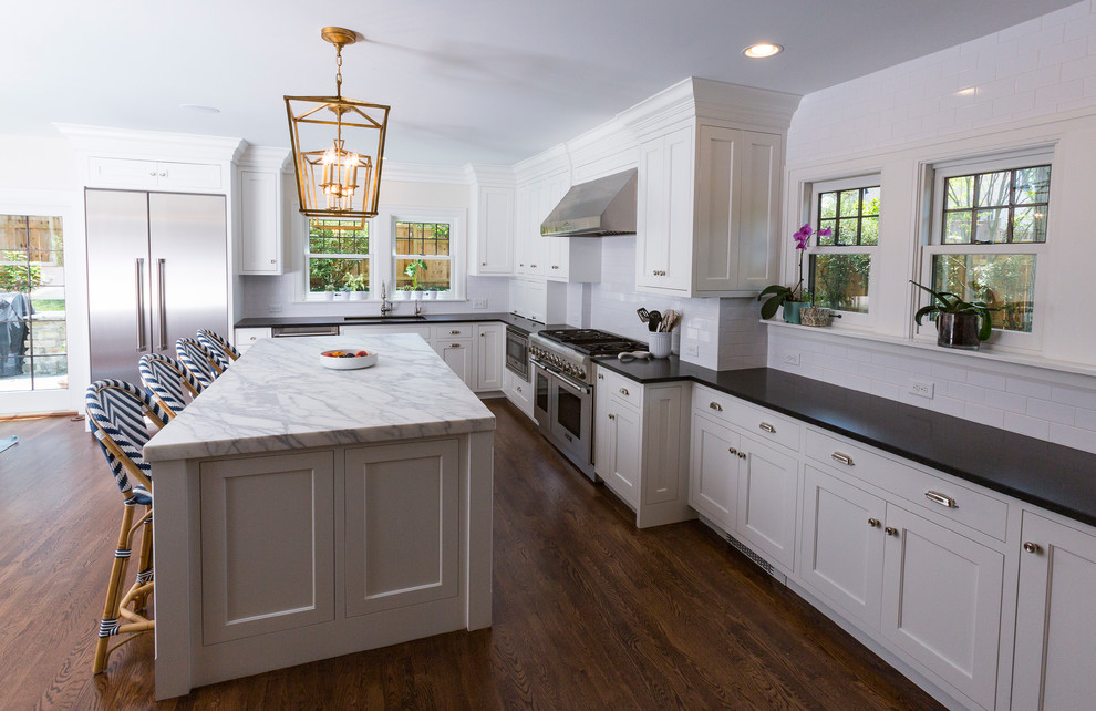 Mid-sized contemporary l-shaped open plan kitchen in Cincinnati with an undermount sink, shaker cabinets, white cabinets, soapstone benchtops, white splashback, subway tile splashback, stainless steel appliances, dark hardwood floors and with island.