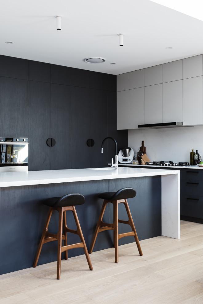 Design ideas for a large contemporary l-shaped kitchen in Moscow with black cabinets, light hardwood floors, white benchtop, white splashback, an integrated sink, flat-panel cabinets, panelled appliances, with island and beige floor.