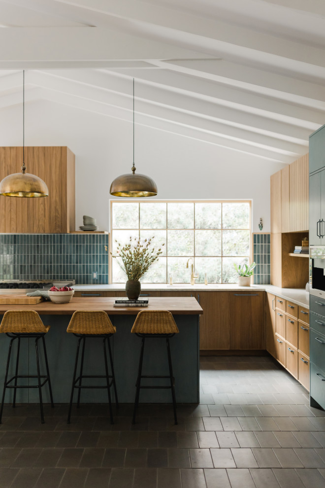Midcentury l-shaped kitchen in Los Angeles with flat-panel cabinets, medium wood cabinets, blue splashback, with island, grey floor, white benchtop, exposed beam and vaulted.