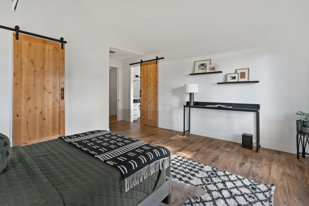 Diseño de habitación de invitados moderna de tamaño medio con paredes blancas, suelo laminado, suelo marrón y madera