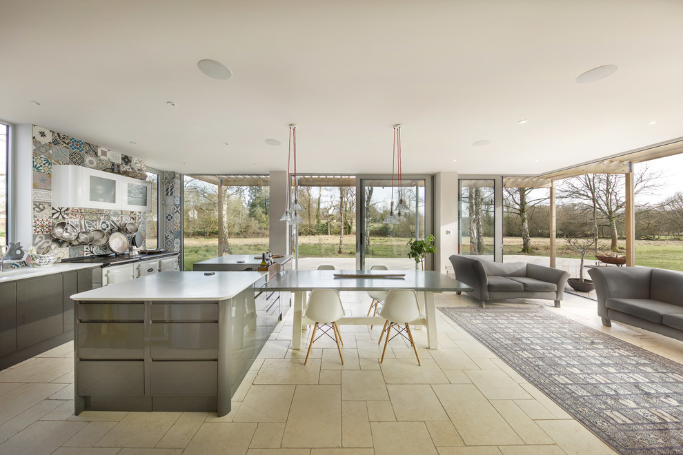 Photo of a contemporary open plan kitchen in Hampshire with flat-panel cabinets, grey cabinets, multi-coloured splashback, white appliances, multiple islands, beige floor and ceramic splashback.