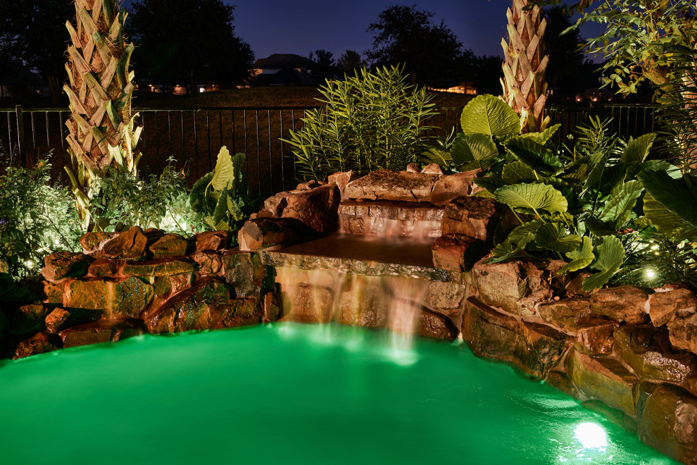 Mid-sized island style backyard stone and custom-shaped pool landscaping photo in Dallas