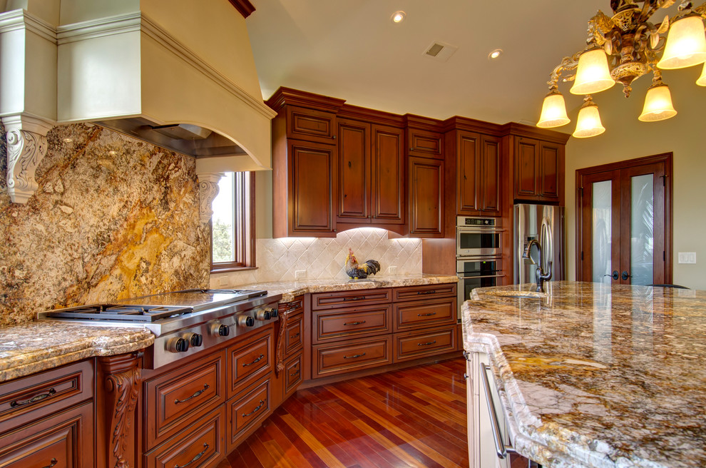 Inspiration for an expansive traditional u-shaped open plan kitchen in Denver with an undermount sink, louvered cabinets, medium wood cabinets, granite benchtops, white splashback, limestone splashback, stainless steel appliances, medium hardwood floors, with island and brown floor.