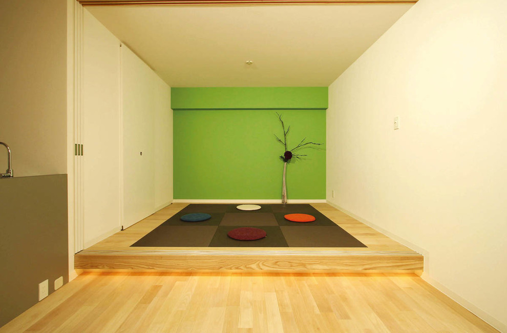 This is an example of an asian family room in Fukuoka with multi-coloured walls and light hardwood floors.