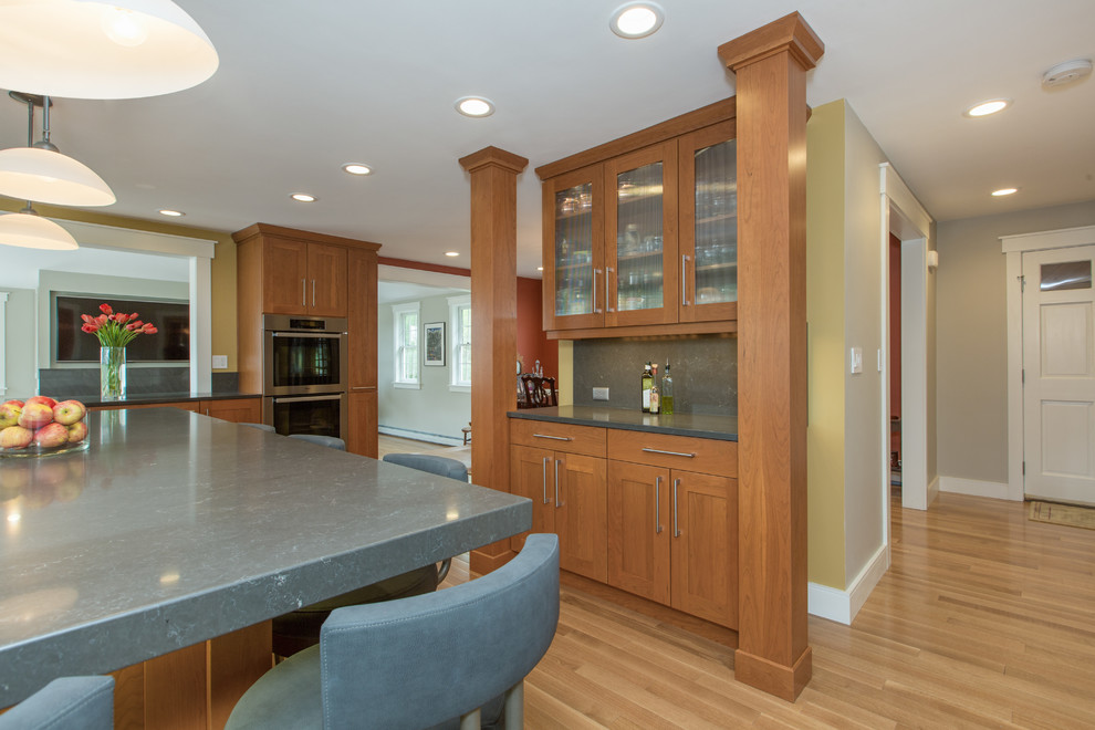 Example of a transitional u-shaped medium tone wood floor kitchen design in Boston with shaker cabinets, an undermount sink, medium tone wood cabinets, quartz countertops, gray backsplash, stone slab backsplash, stainless steel appliances and an island