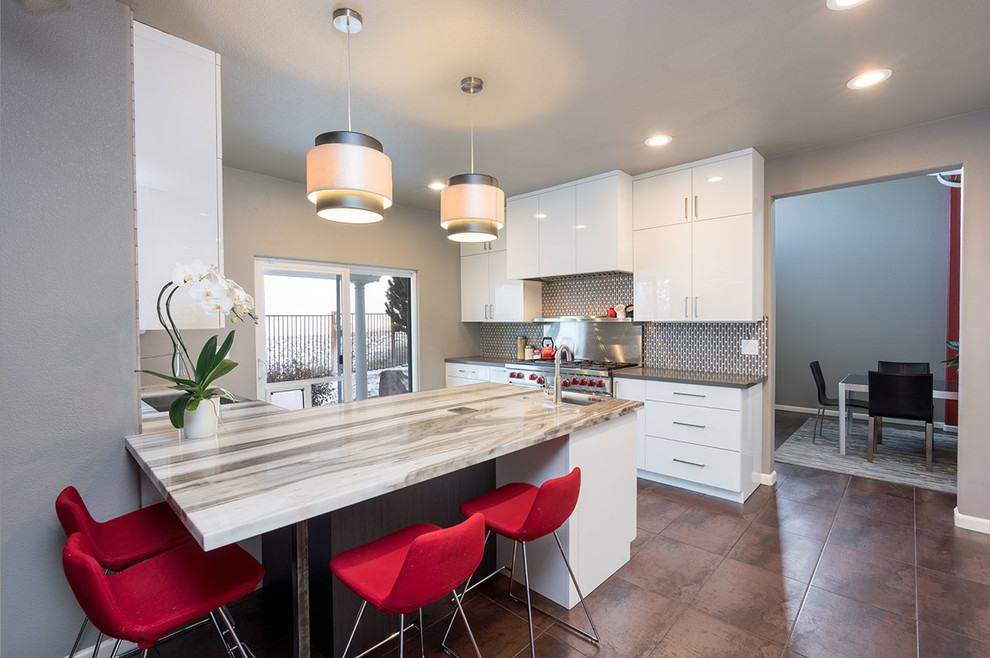 Example of a trendy porcelain tile and brown floor kitchen design with flat-panel cabinets, white cabinets, gray backsplash, stainless steel appliances and an island