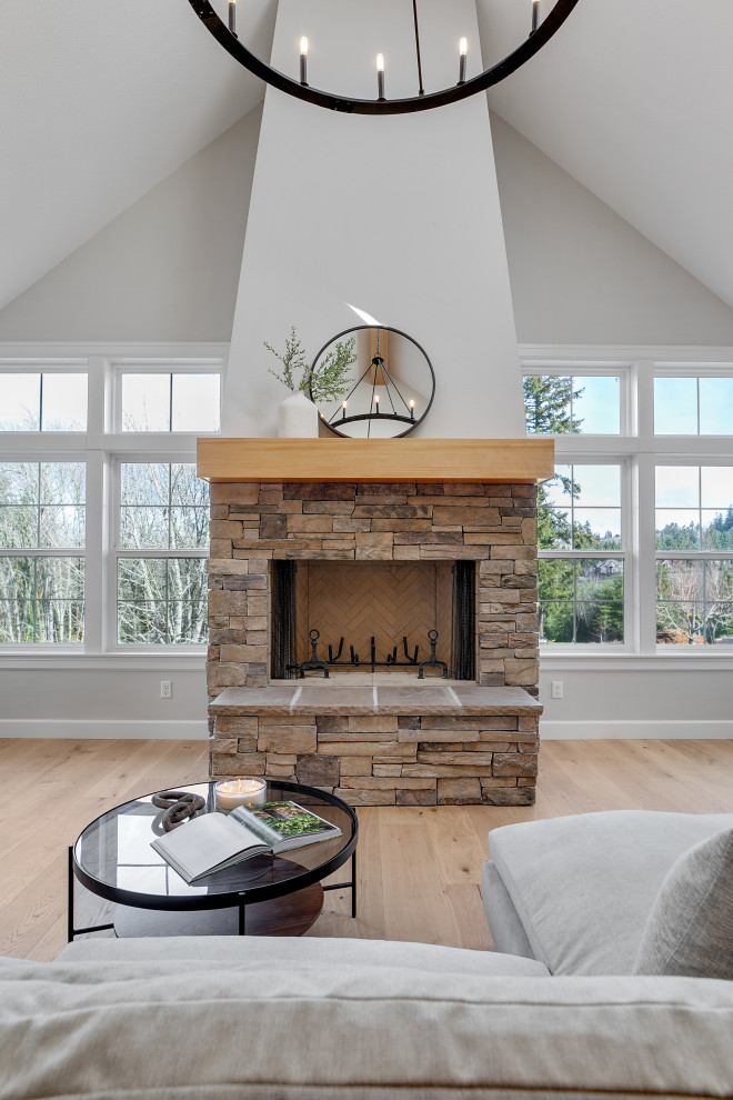 Photo of an expansive transitional open concept living room in Portland with a home bar, grey walls, light hardwood floors, a wood stove, no tv, brown floor and vaulted.