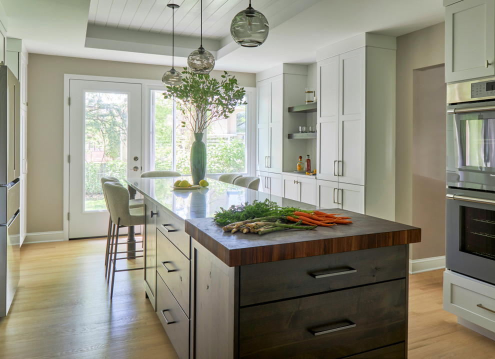 Large transitional u-shaped light wood floor, brown floor and coffered ceiling eat-in kitchen photo in Chicago with a farmhouse sink, shaker cabinets, white cabinets, quartz countertops, white backsplash, subway tile backsplash, stainless steel appliances, an island and multicolored countertops