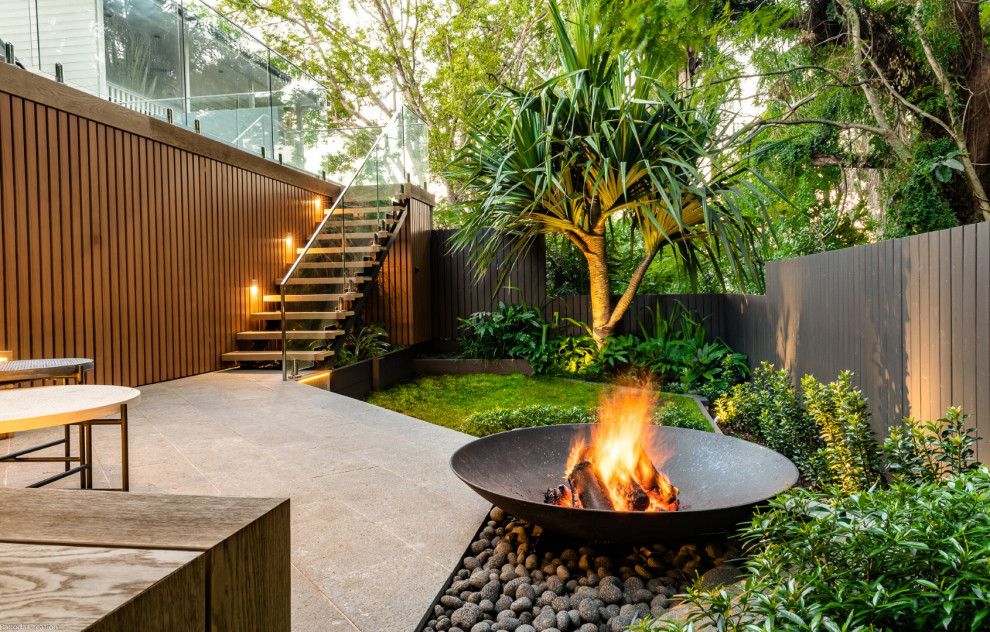 This is an example of a small contemporary courtyard partial sun garden for summer in Brisbane with natural stone pavers.