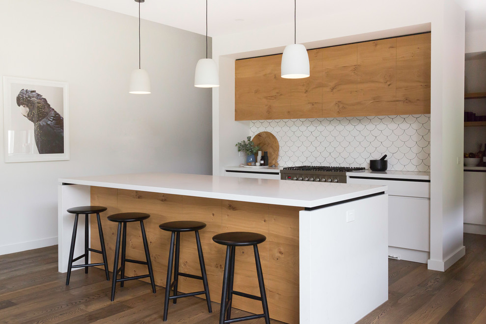 Inspiration for a mid-sized contemporary galley open plan kitchen in Melbourne with a drop-in sink, flat-panel cabinets, white cabinets, quartz benchtops, white splashback, ceramic splashback, stainless steel appliances, ceramic floors, with island, brown floor and white benchtop.