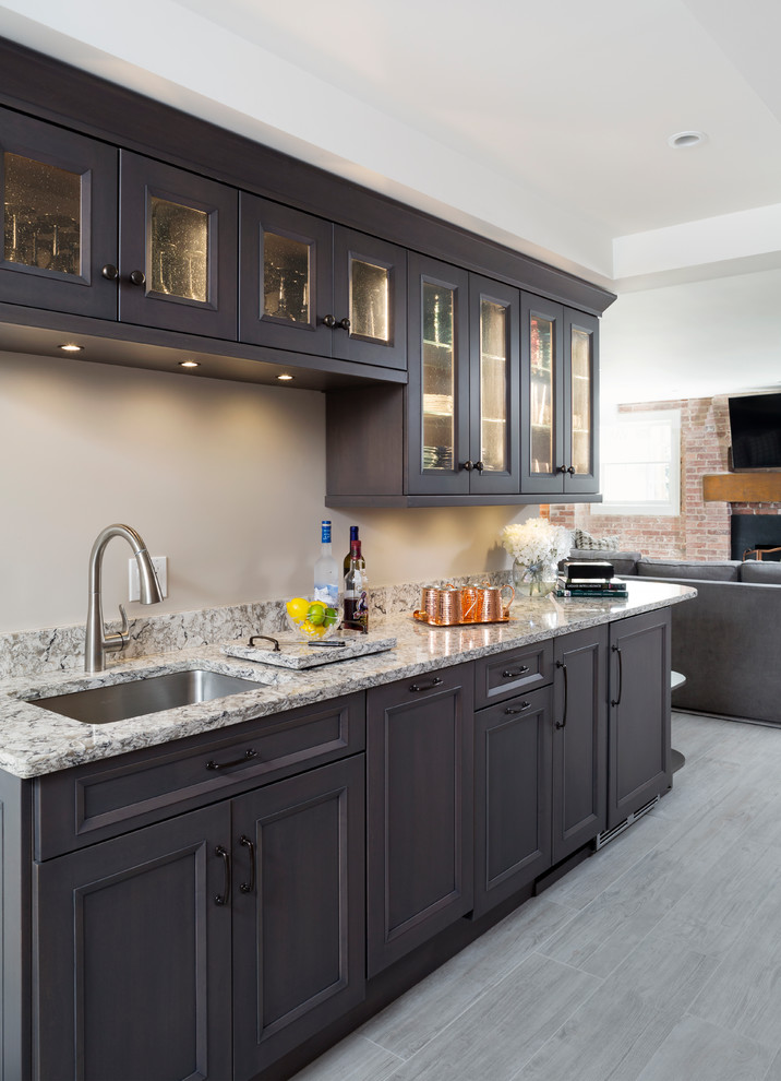 Inspiration for a mid-sized traditional single-wall wet bar in DC Metro with an undermount sink, glass-front cabinets, black cabinets, granite benchtops, grey floor and porcelain floors.