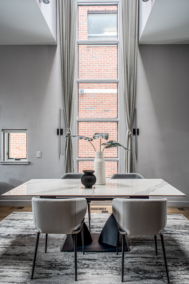 Foto di una sala da pranzo aperta verso il soggiorno minimal di medie dimensioni con pareti grigie, parquet chiaro e pavimento grigio
