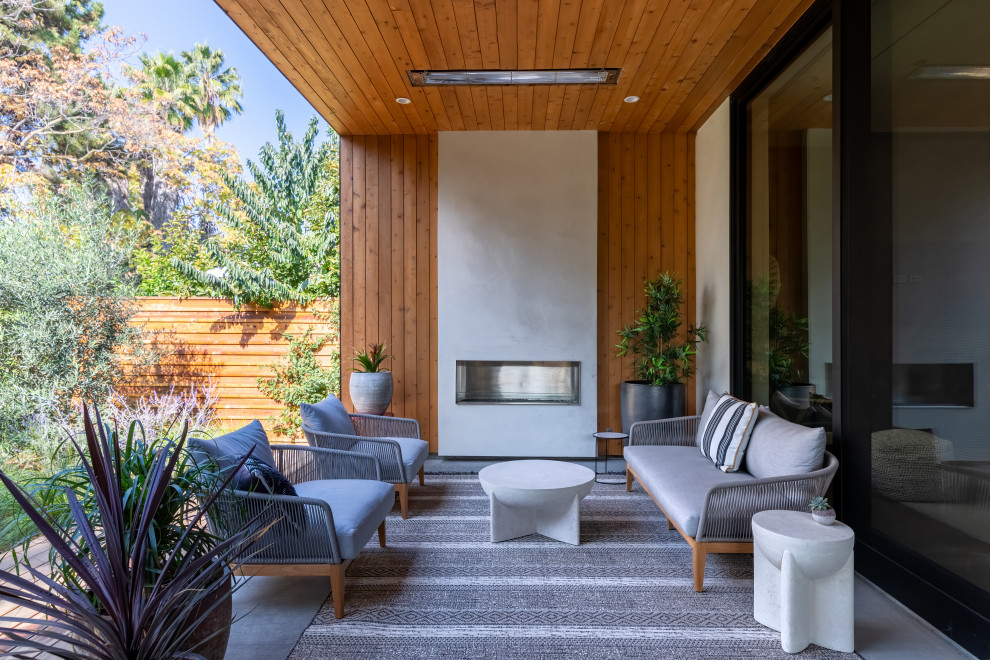 Imagen de patio contemporáneo en anexo de casas con chimenea y losas de hormigón