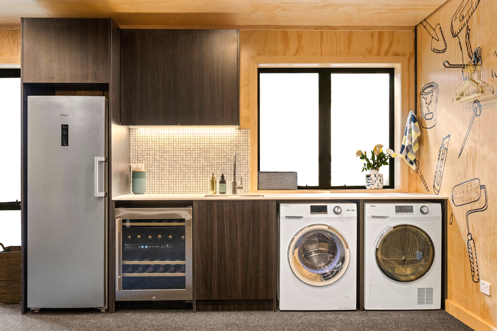 Design ideas for a contemporary single-wall laundry room in Auckland with an undermount sink, flat-panel cabinets, dark wood cabinets, brown walls, a side-by-side washer and dryer and grey floor.