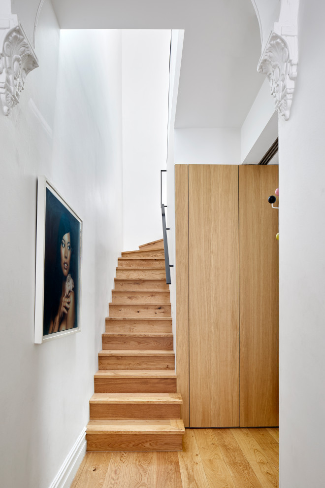 Cette image montre un petit escalier design en L avec des marches en bois, des contremarches en bois et un garde-corps en métal.
