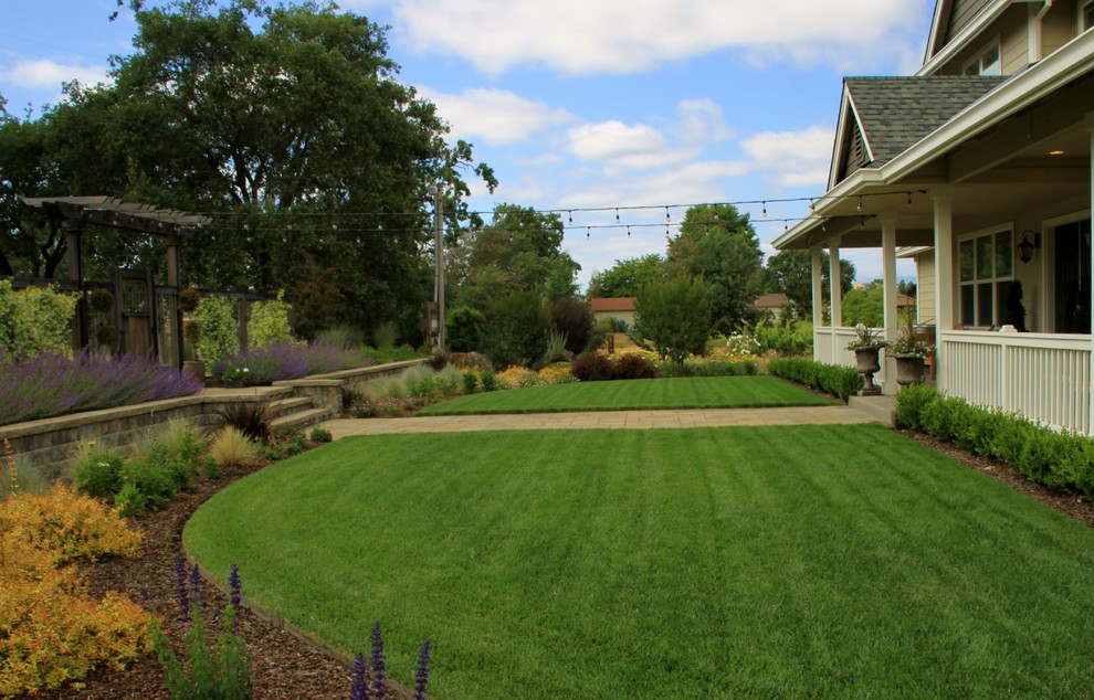 This is an example of an expansive country front yard full sun formal garden for summer in San Francisco with a retaining wall and concrete pavers.