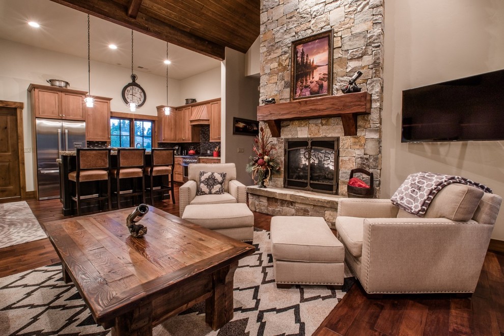 This is an example of a country open concept living room in Other with grey walls, medium hardwood floors, a standard fireplace, a stone fireplace surround and a wall-mounted tv.