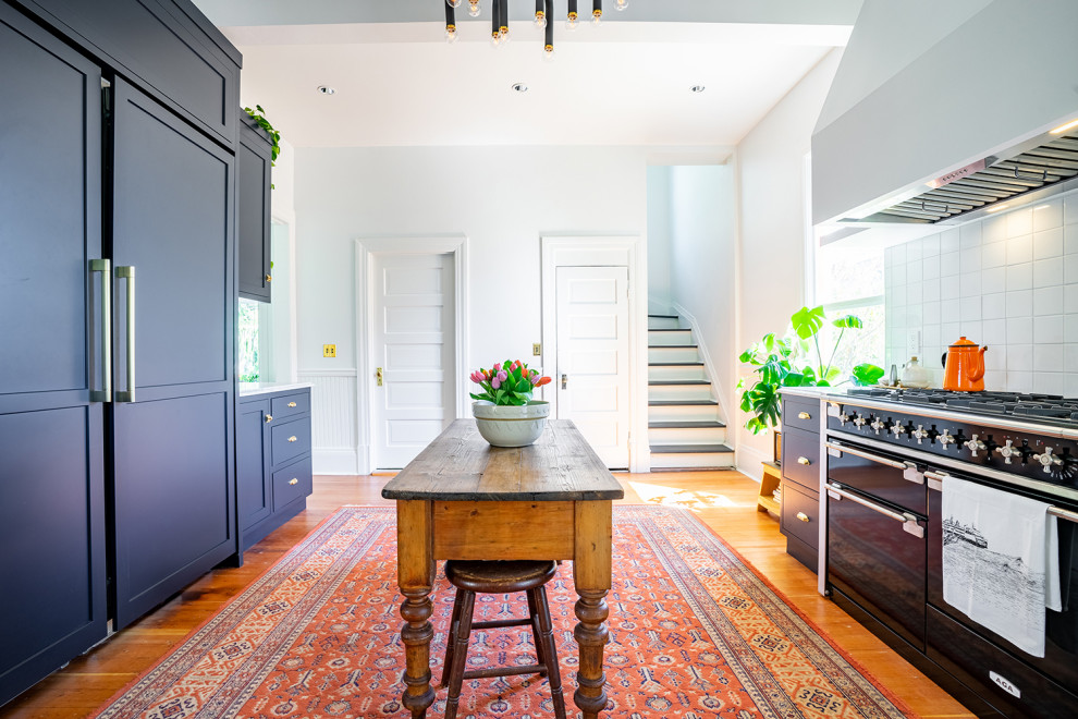 Bild på ett avskilt, stort eklektiskt grå grått u-kök, med en nedsänkt diskho, skåp i shakerstil, blå skåp, marmorbänkskiva, vitt stänkskydd, stänkskydd i keramik, mellanmörkt trägolv och en köksö
