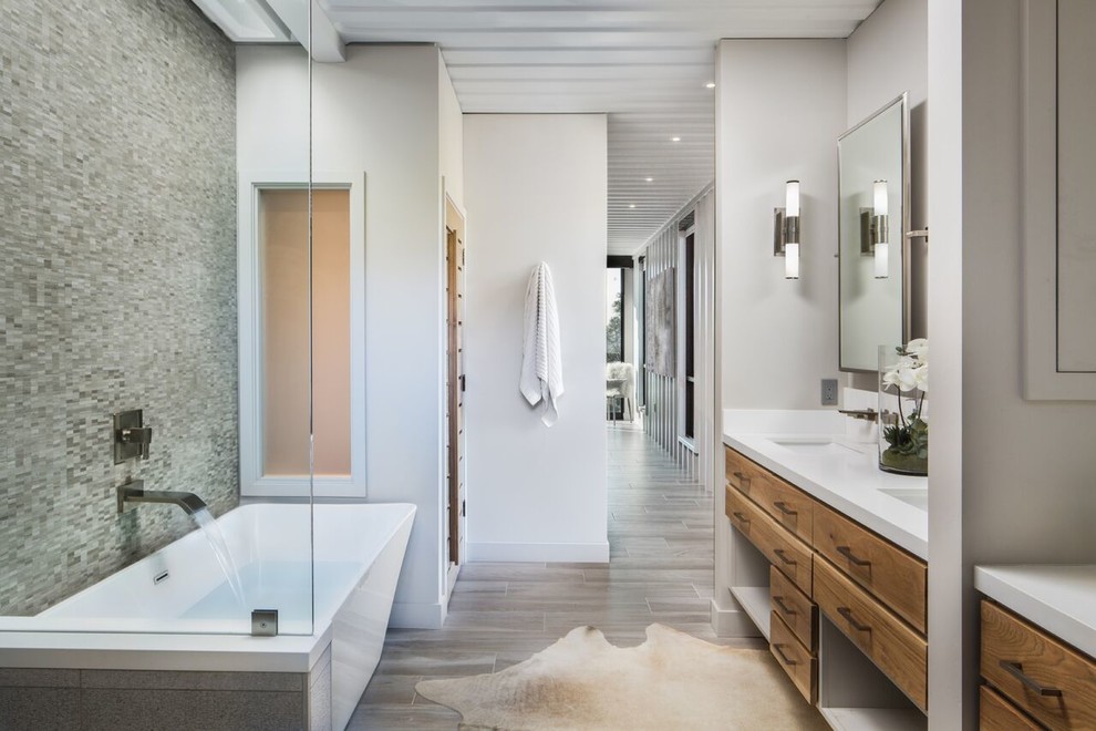 Industrial master bathroom in Santa Barbara with flat-panel cabinets, medium wood cabinets, a freestanding tub, an alcove shower, gray tile, mosaic tile, white walls, an undermount sink, beige floor, a hinged shower door and white benchtops.