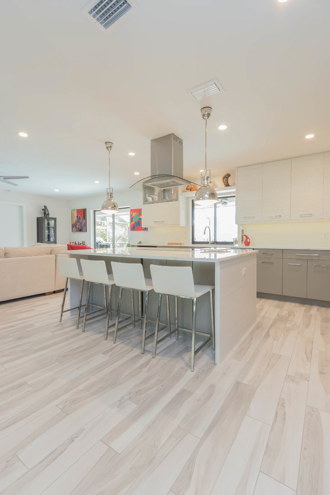 This is an example of a large modern l-shaped open plan kitchen in Other with an undermount sink, flat-panel cabinets, grey cabinets, quartz benchtops, ceramic splashback, stainless steel appliances, porcelain floors, with island and grey floor.