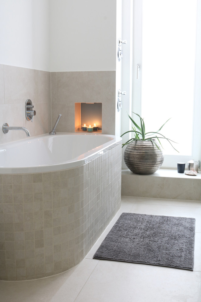 Mid-sized contemporary master bathroom in Berlin with a drop-in tub, a wall-mount toilet, beige tile, white walls and beige floor.