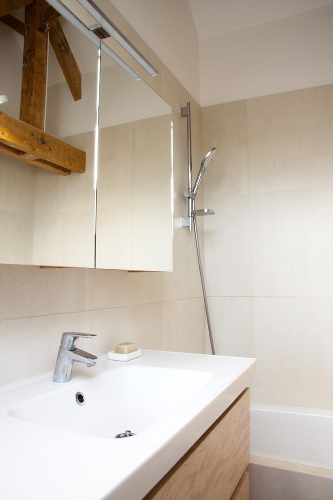 This is an example of a small scandinavian master bathroom in Paris with flat-panel cabinets, brown cabinets, an undermount tub, a shower/bathtub combo, a one-piece toilet, white tile, porcelain tile, beige walls, ceramic floors, a console sink, beige floor, an open shower and white benchtops.