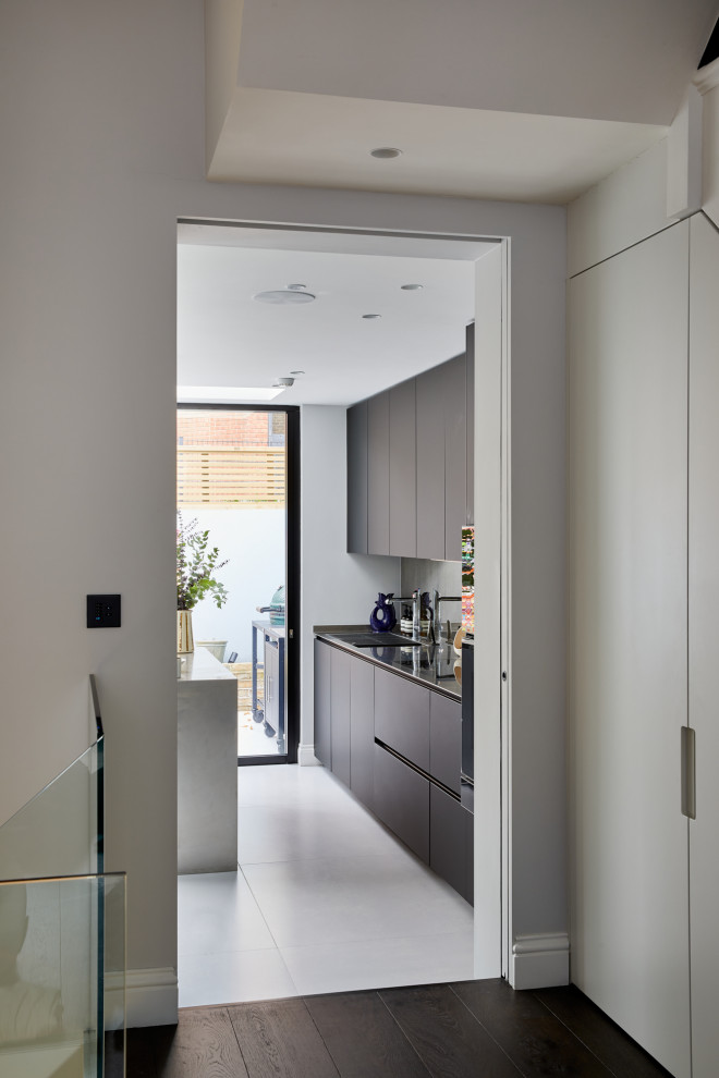 Inspiration for a small modern single-wall kitchen/diner in London with flat-panel cabinets, black cabinets, stainless steel worktops and an island.