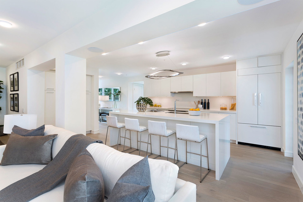 Design ideas for a mid-sized contemporary galley open plan kitchen in Miami with an undermount sink, flat-panel cabinets, white cabinets, panelled appliances, dark hardwood floors, with island, brown floor, white benchtop, solid surface benchtops, white splashback and porcelain splashback.