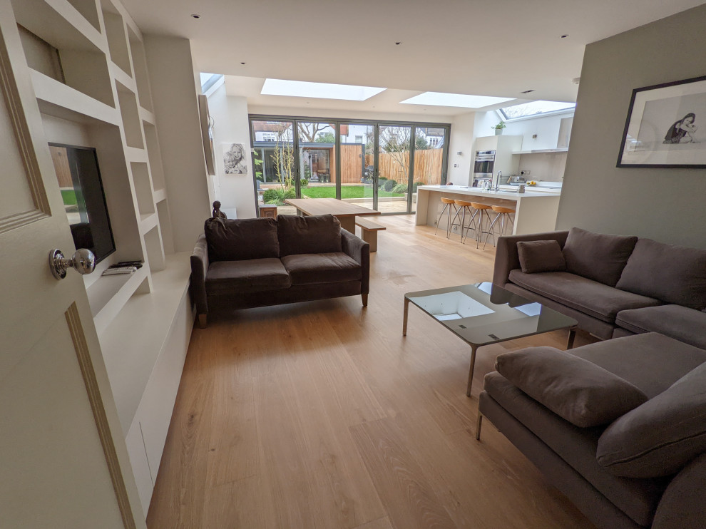 Foto di un grande soggiorno minimalista aperto con pavimento in legno massello medio