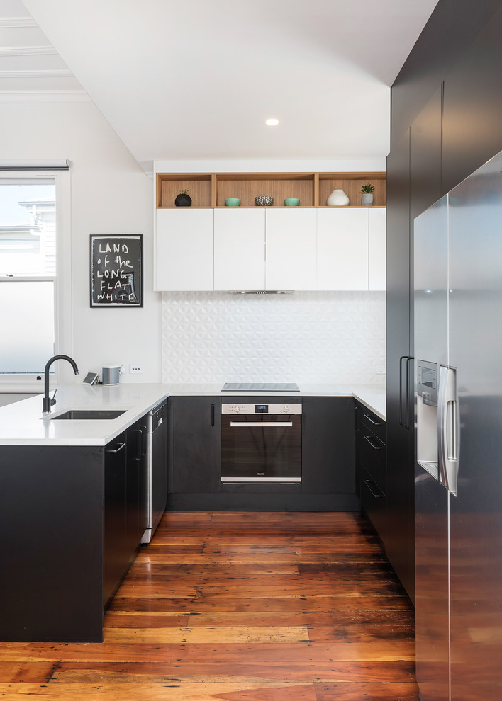Inspiration for a mid-sized modern u-shaped eat-in kitchen in Auckland with an undermount sink, flat-panel cabinets, black cabinets, laminate benchtops, white splashback, ceramic splashback, stainless steel appliances, medium hardwood floors and brown floor.